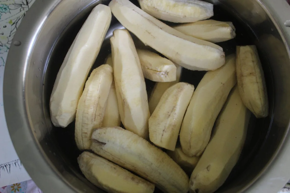Peeled green bananas soaking in a pot of water, the first step in making guineitos en escabeche