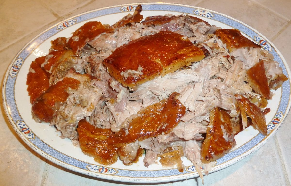 carved puerto rican pernil with crisp cuerito pieces served alongside the pulled pork