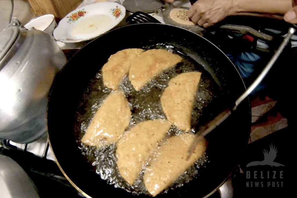Frying Belizean empanades in a cast iron pan, the oil is very hot. The panades cook quickly. 