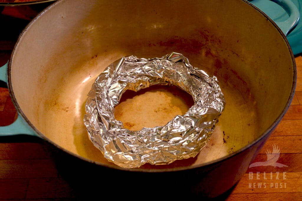 A foil donut in the bottom of Dutch oven helps keep the pork off the bottom of the pot to prevent scorching.