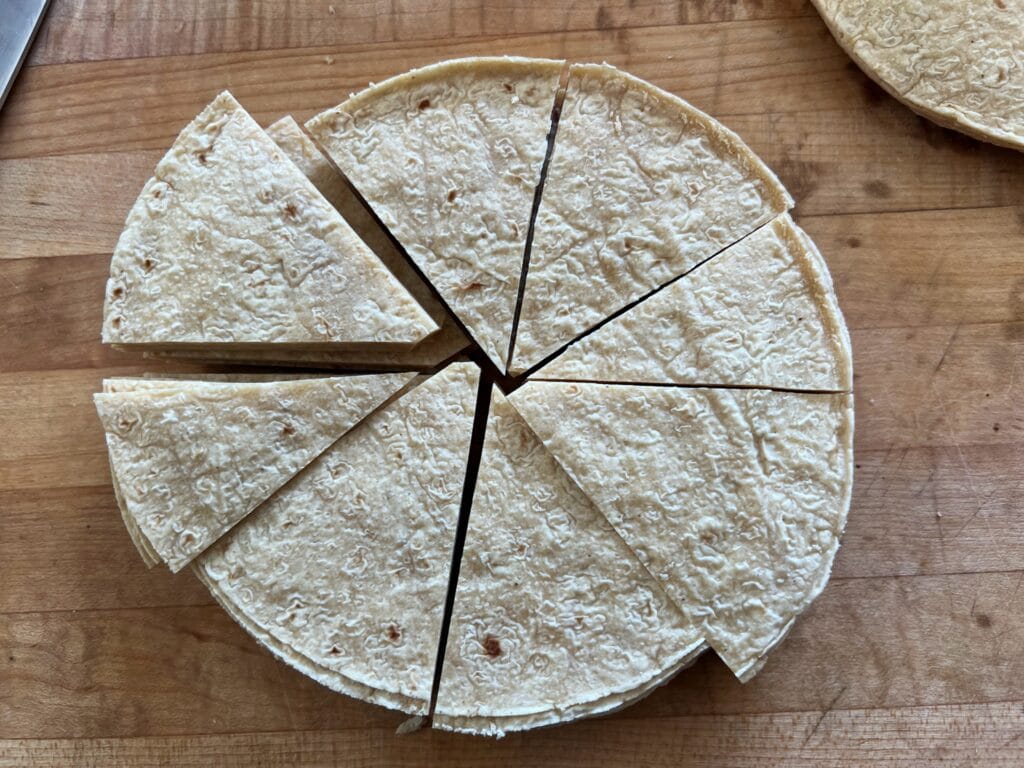 Cutting a tortillas in pie wedge shape before frying. 