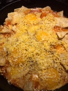 A layer of cheese added to cooked eggs and fried corn tortillas