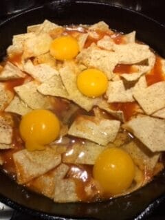 Fresh eggs added on top of corn tortilla chips and tomato sauce