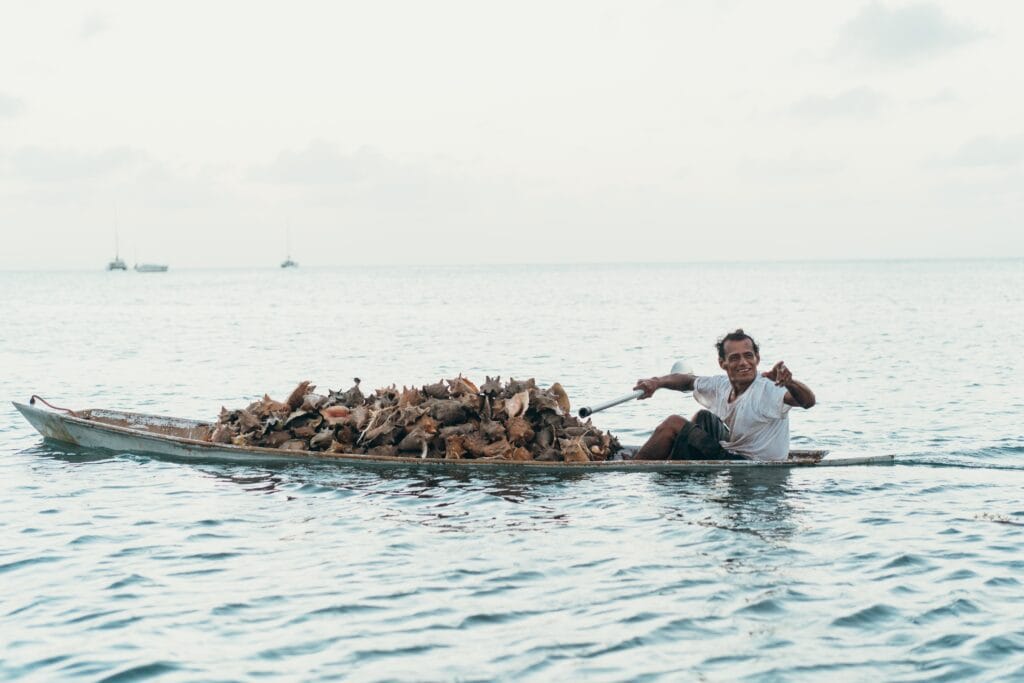 Conch Fisherman in Belize with his dory loaded with freshly caught conch.