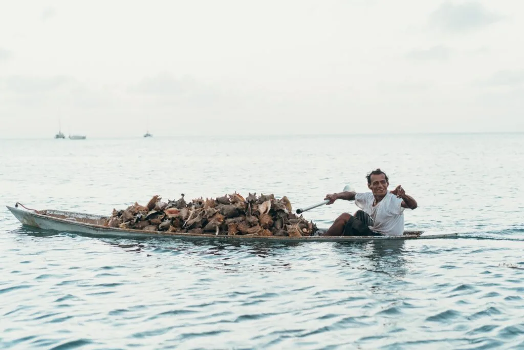 Conch Fisherman in Belize with his dory loaded with freshly caught conch.