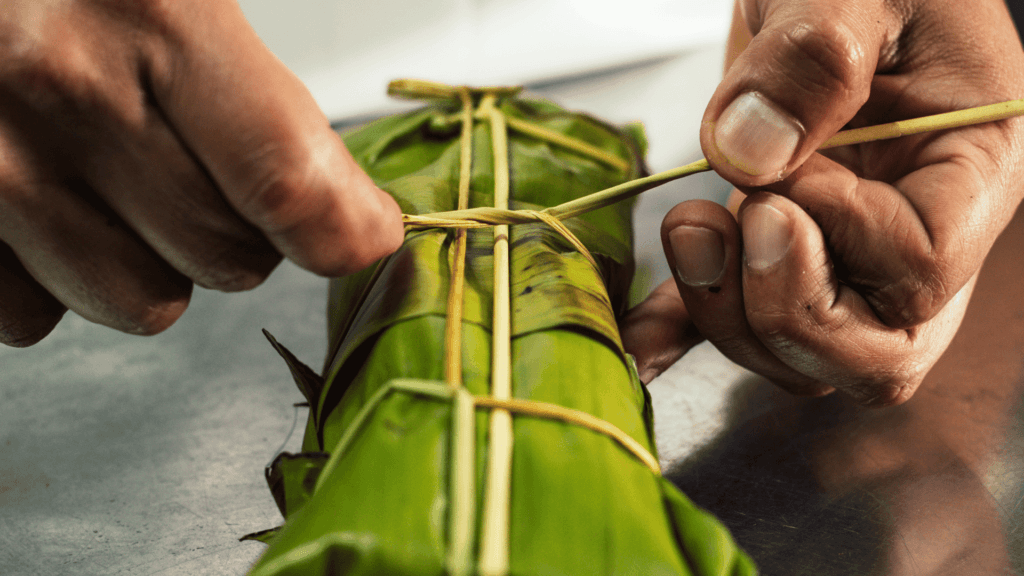 Tying banana leaf wrapper around Tamales