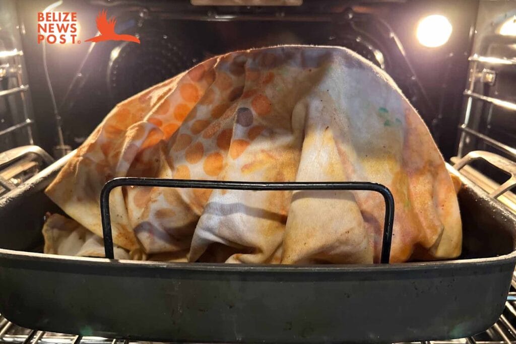 Turkey is covered with an oil soaked cloth for roasting on a rack in roasting pan.