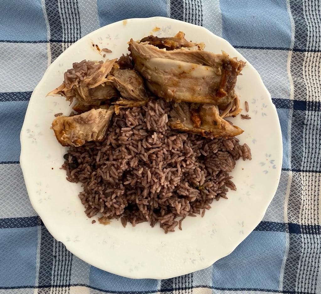 A plate of Cuban congri served with roast pork, the rice grains dark and separate
